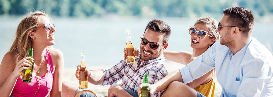 Group of friends sitting on beach with picnic beers - Henry's store locations